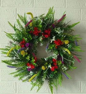 Detailed view of artificial wildflower wreath with red and purple blooms on a white wall