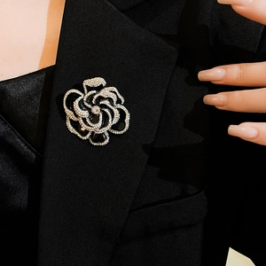 Detailed view of a black flower brooch with sparkling crystals on a black suit lapel