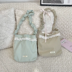 Close-up of lace-trimmed plaid canvas tote bags with ruched straps on a soft white sofa