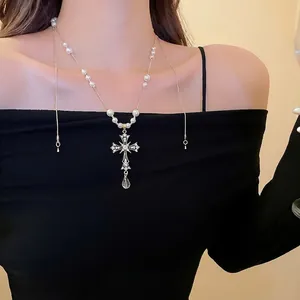 Cross necklace with pearls and rhinestones on a model against a minimalist background