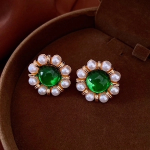 Macro detail of vintage gold flower stud earrings with green emerald gemstone and pearls