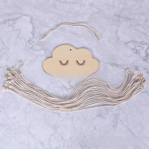Close-up of wooden cloud wall decor with carved eyelashes and hanging cotton ropes