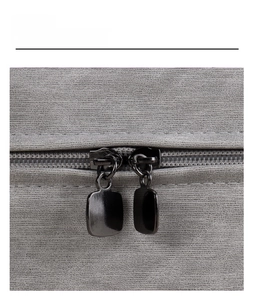Detailed macro view of smooth dual gunmetal zippers on gray textured cosmetic bag fabric