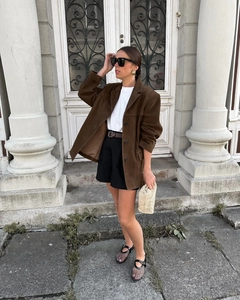 Style de rue d'une femme en blazer en daim marron foncé avec sac en paille et mary janes