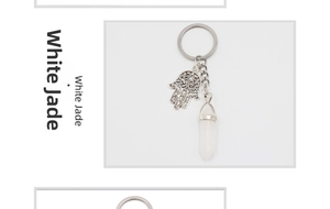 Macro shot of white jade hexagonal crystal pendant with a metal Hamsa Hand keychain