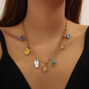 Gold chain necklace with ocean-themed ceramic and metal charms worn by a model