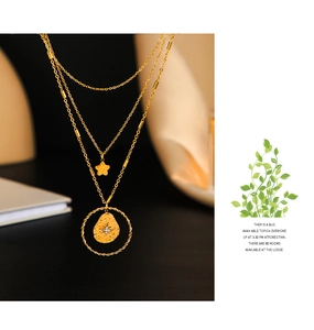 Macro detail of 14K gold layered necklace featuring a star pendant and hammered disc