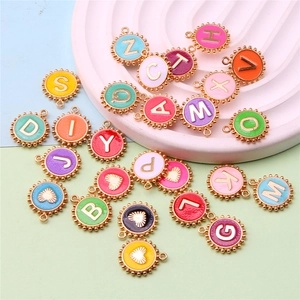 Colorful enamel alphabet pendants and heart charms scattered on a pastel decorative plate