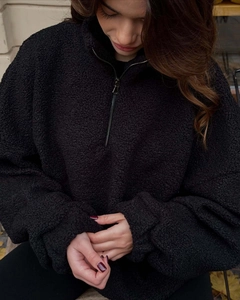 Detail of black faux shearling fleece texture and half-zipper collar on warm winter pullover