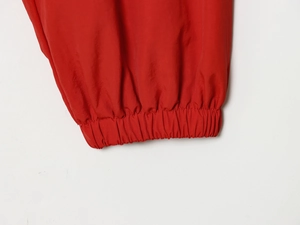 Close-up of red nylon jacket showing elastic cuff and smooth woven fabric texture