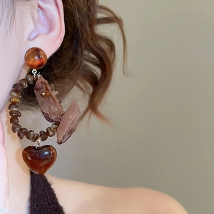Detail of vintage heart-shaped resin drop earrings in dark brown worn by model