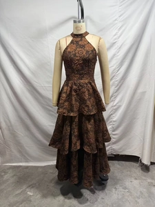 Détail de l'ourlet à volants d'une robe longue dos nu en jacquard floral marron foncé et or