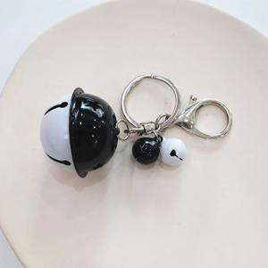 Detail of black and white cartoon bell keychain with a woven rope and metal lobster clasp