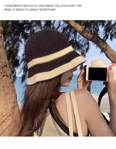Detail view of a knitted striped bucket hat in brown with sea view backdrop