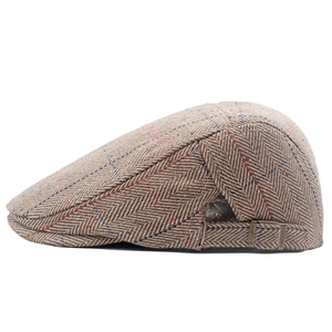 Detail view of adjustable bronze buckle on brown herringbone tweed ivy cap