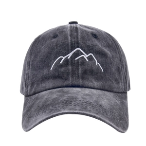 Close-up of white mountain peak embroidery on a washed dark grey cotton baseball cap