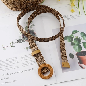 Close-up of a brown woven elastic belt with a round wooden buckle and PU leather details