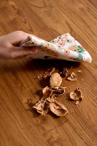 Detail einer Serviette mit Lebkuchenmann-Aufdruck über Walnussschalen auf dem Holztisch