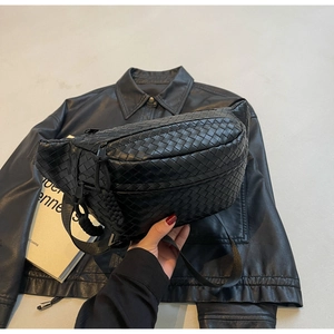 Detail of black woven texture on fashionable sling bag with adjustable strap and leather finish