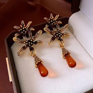 Vintage bronze flower earrings with amber water drop pendants on brown silk background