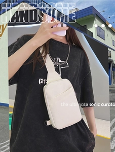 Detail of off-white canvas chest bag showing the thick texture and adjustable strap