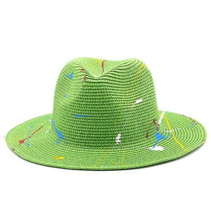 Macro detail of grass green woven fedora hat with artistic colorful paint splatters