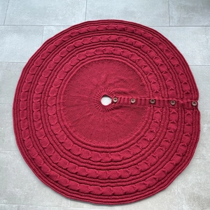 Detail of red cable knit Christmas tree skirt with decorative wooden buttons