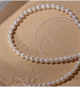 Macro shot of 7mm natural white freshwater pearls in S-curve on fine sand texture