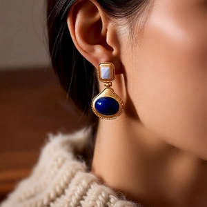 Detail view of vintage gold-tone earrings with blue gemstones on a female model