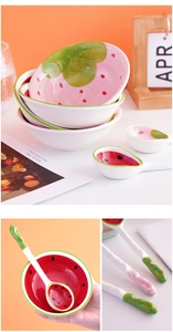 Detail of cute ceramic fruit bowls and spoons with strawberry and watermelon patterns