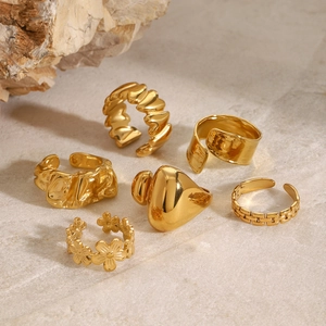 Flat lay of a six-piece gold vintage ring set with heart and floral designs on stone