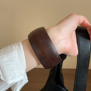 Detailed view of the dark brown resin bangle with natural wood grain texture and glossy finish