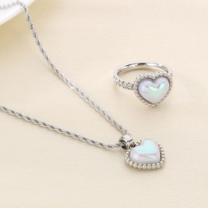 Macro shot of silver heart jewelry set with iridescent inlay and twisted chain details