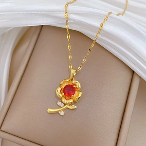 Elegant gold-tone rose necklace with red gemstone and crystal leaves on silk background