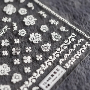 3D white floral nail stickers with thin embossed flower and leaf patterns on gray background