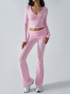 Close-up detail of pink V-neck cropped long sleeve top and flared knit trousers set