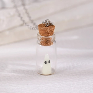 Macro shot of glass bottle necklace featuring a cute white ghost and natural cork stopper