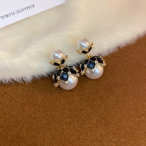 Macro detail of French vintage pearl earrings with gold plating and black enamel accents