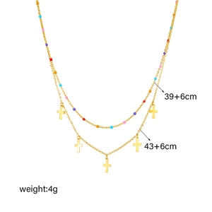 Detail of gold double-layer necklace with colorful beads and small cross charms