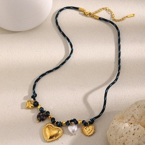 Detail of 18K gold heart charms and pearls on a black woven cord vintage necklace
