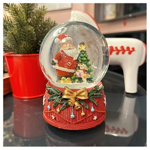 Detail of Christmas snow globe with Santa and dog figures on a red knitted texture base