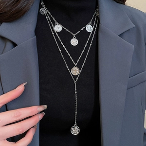 Close-up of triple layered silver coin pendant necklace styled on a grey blazer outfit