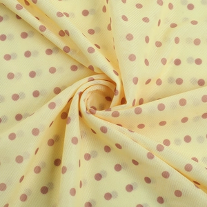 Dettaglio macro del tessuto a rete giallo chiaro traspirante a pois marroni per abito lungo