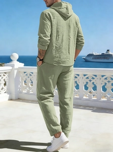 Back view of men's linen hoodie and pants set in sage green at a seaside terrace