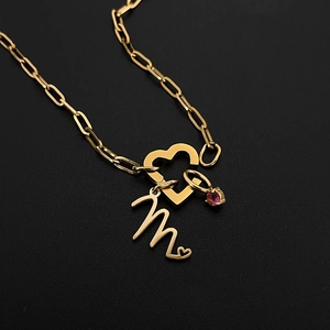 Detail view of gold-tone paperclip chain necklace with heart clasp and letter 'm' charm