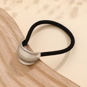 Detailed view of black elastic hair band with silver crescent metal piece on wood