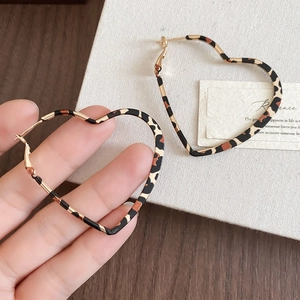 Close-up of leopard print heart-shaped hoop earrings with a metallic gold finish