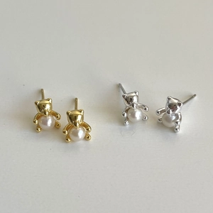 Detail view of bear shaped pearl earrings in gold and silver metal finishes