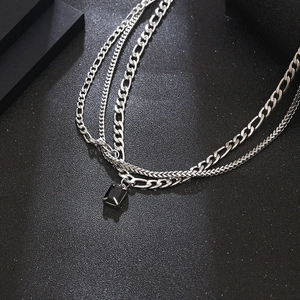 Layered silver titanium steel necklace with black square gemstone pendant on dark background