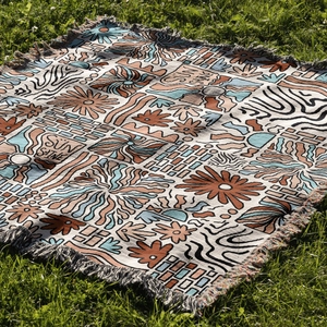 Macro detail of bohemian woven camping blanket with sun pattern and fringed edges on grass